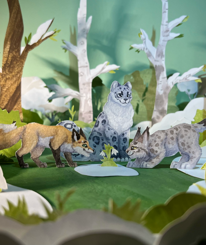 Paper craft diorama of a fox, snow leopard and a lynx in the spring forest